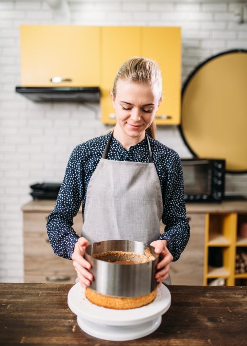 Woman cook in apron takes the form of a baked cake.jpg